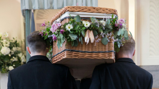 Two men carrying a casket at a funeral service